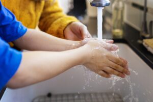 Deux enfants qui se lavent les mains au robinet